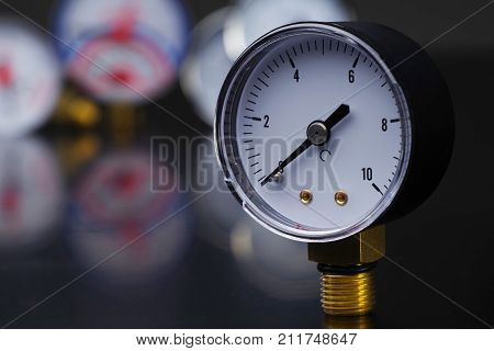 Dark surface with a deep reflection of pressure gauges.manometer in focus. A pressure gauge on the background of other instruments.