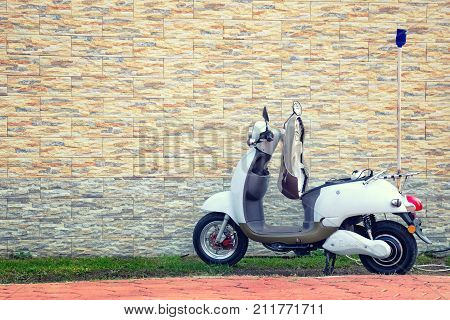 Batumi Georgia - October 22 2017: Electric motor scooter parked near a beautiful wall for charging. Empty copy space for text.