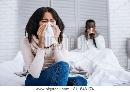 Endless flu. Tired ill young sneezing couple hopelessly curing their terrible flu