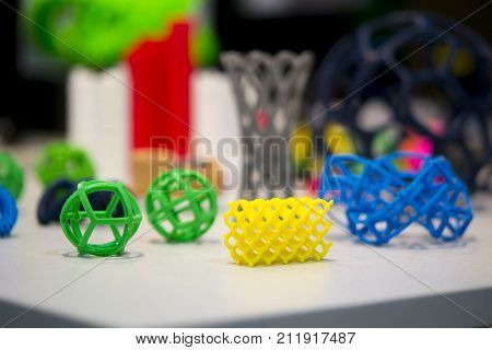 Many abstract models bright colorful objects printed on a 3d printer on a white table. Fused deposition modeling, FDM. Progressive modern additive technology. Concept of 4.0 industrial revolution