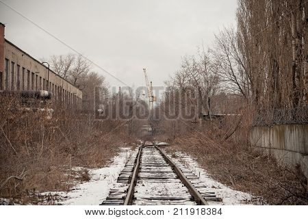Narrow-gauge railway in industrial area. Snowfall with the fog.
