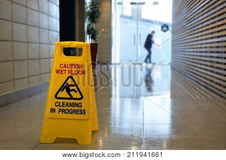 Slippery floor surface warning sign and symbol on a wet floor of unrecognizable building hallway.
