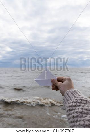 Close-up of human hand paper boat sea vague backround