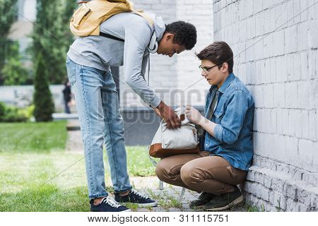 Aggressive African American Boy Taking Backpack From Frightened Boy In Glasses
