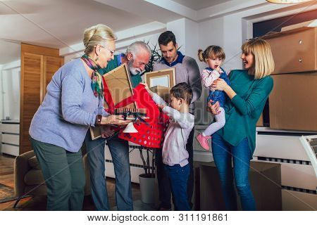 Grandmother And Grandfather Bring A Gift For Moving Into A New Apartment To Their Children