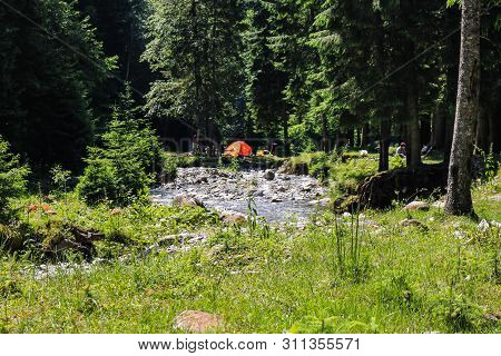 Iezer Mountains - Romania - 2019. People Relaxing Next To A River, And Having Barbeque.