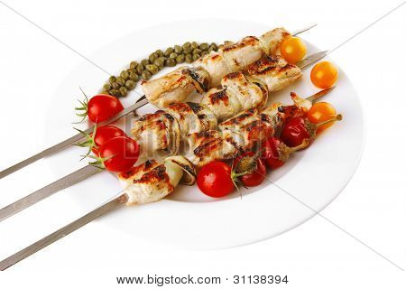 svinekød shish kebab på hvidt fad med grøntsager