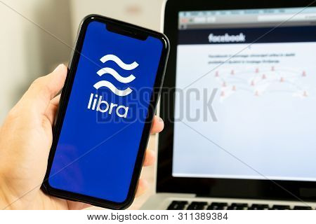 12 July 2019, Ljubljana Slovenia - Hand Holding Smartphone With Libra Logo Next To Facebook Webpage.