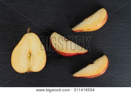 Group Of One Half Three Slices Of Fresh Dark Red Pear Anjou Flatlay On Grey Stone