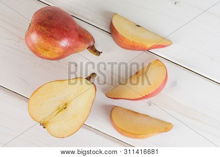 Group Of One Whole One Half Three Slices Of Fresh Dark Red Pear Anjou Flatlay On White Wood