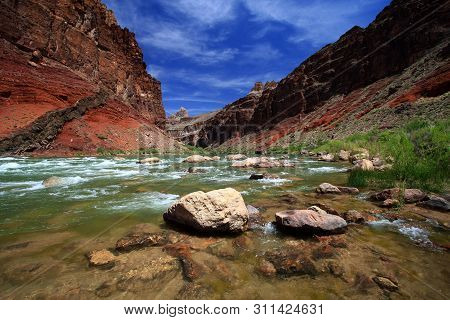 Hance Rapids In Grand Canyon National Park, Arizona, With Red Canyon Walls Under A Deep Blue Sky.