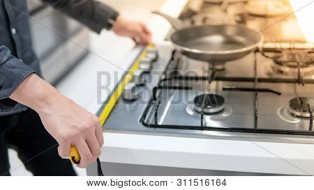 Male Hand Interior Designer Using Tape Measure On Gas Stove On Modern Countertop In Kitchen Showroom