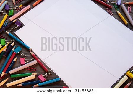 Background With Paper And Crayons On A Wooden Table.