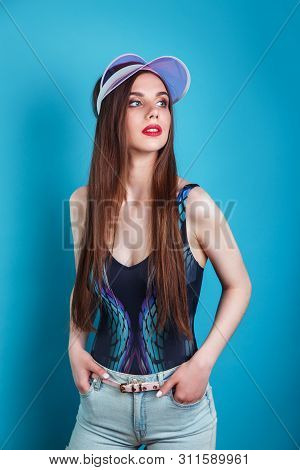 Portrait Of Beautiful Woman Wearing A Sunvisor Posing On Blue Background.