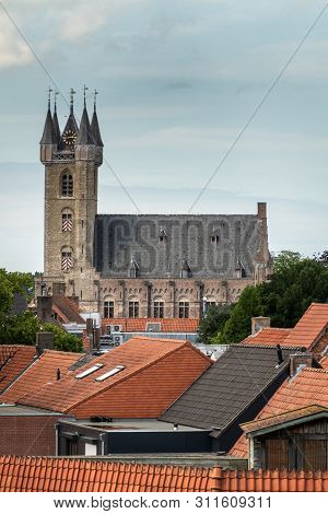 Sluis, The Netherlands -  June 16, 2019: View Over Red Roofs At The Brown Brick Belfry With Clock To