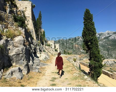 A Young Female Tourist Walking Around The Medieval Fortress Of Klis On A Beautiful Summer Day.the Kl