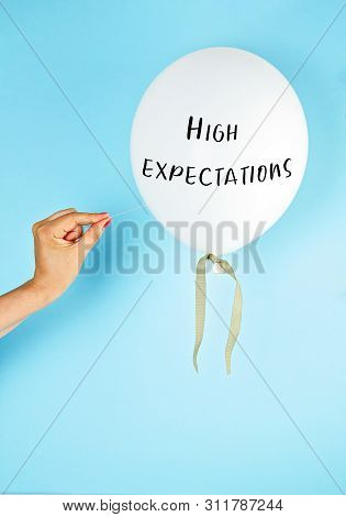 Balloon With High Expectation Text And The Hand With The Needle Directed To The Balloon. Disappointm