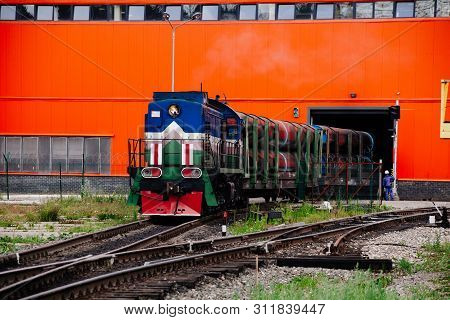 Freight Train With New Manufactured Pipes Exits From Warehouse.