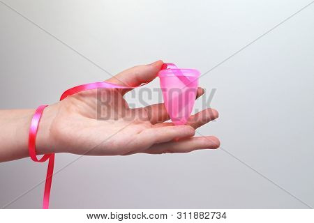 A Woman Holds A Menstrual Cup In Her Hand On A Pink Background. The Concept Of Women's Health, Hygie