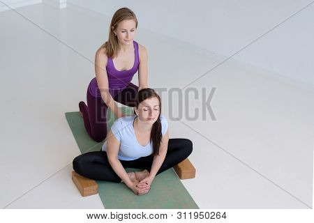 Two Women Practicing Yoga, Doing Butterfly Exercise, Baddha Konasana With Props