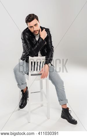 Bearded Stylish Man Sitting On Shite Chair On Grey Background