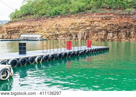 Floating Platform Made Of Barrels And Tires In The Middle Of The Lake. Floating Walkway. Photo Taken