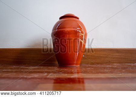 Orange Urn Leaning Against The White Wall