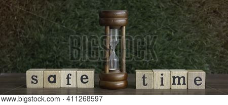 Sandclock Put At The Middle Of Safe Time Word Written On Wood Block,blurry Light Around