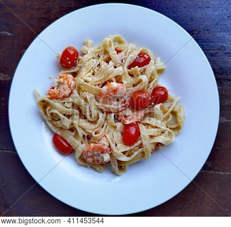 Creamy Pasta With Shrims And Cherry Tomatos On The White Plate
