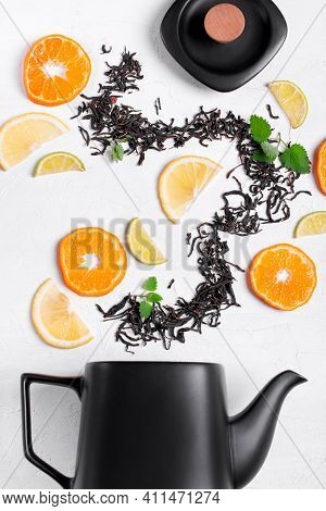 Dry Tea Leaves, Tangerine, Orange, Lime Slices And Mint Arranged In A Wave On The White Table. Tea I