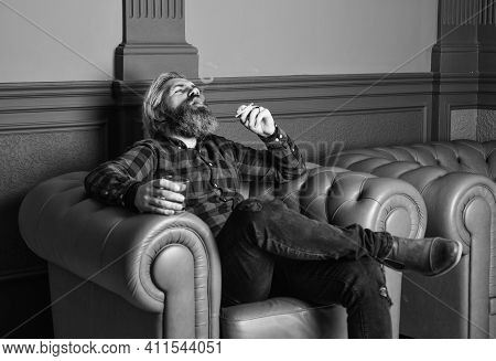 Confident Bearded Male Sit In Luxury Leather Armchair. Luxury And Success. Smoke Cigarette While Dri