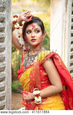 Portrait Of Pretty Young Indian Girl Wearing Traditional Saree And Jewellery, Playing With Colors On