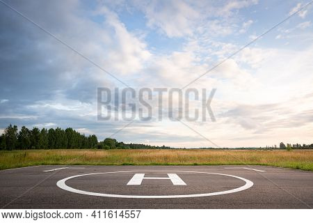 View Of The Private Helipad On A Warm Summer Evening. An Asphalt Helipad Against The Backdrop Of A G
