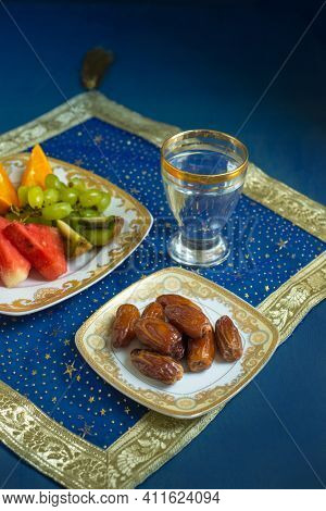 Sweet Arabian dates and fresh fruit slices with glass of water. Iftar is the time to replenish energy levels from healthy and nutritious foods.