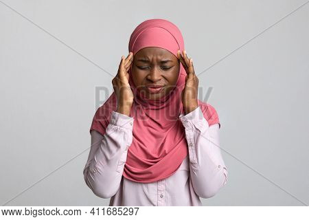 Upset Young Muslim African American Woman In Hijab Having Headache, Touching Her Head, Closing Eyes,