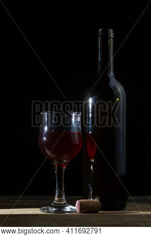 A Glass Of Homemade Wine Next To A Bottle On A Dark Background. Glass Of Red Wine On A Black Backgro