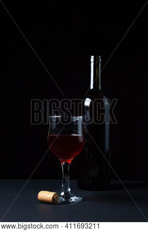 A Glass Of Homemade Wine Next To A Bottle On A Dark Background. Glass Of Red Wine On A Black Backgro