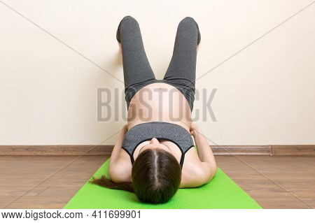 Beautiful Young Pregnant Woman Sitting On Mat In Yoga Pose At The Home. Pregnancy Yoga And Fitness C