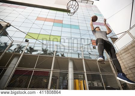 Young Asian Basketball Player Going Up For A Layup On Outdoor Court