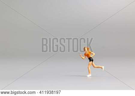 Miniature People Running On Gray Background