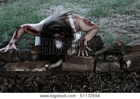 Woman zombie crawls out toward her victim