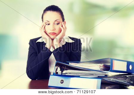 Sad woman with ringbinders sitting at the desk. Tired and exhousted business woman.