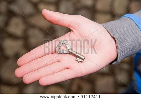 Child's Hand Holding One Old Key