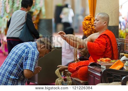 SANGKHLABURI, THAILAND, JANUARY 24, 2016 :  A skilled Buddhist monk is blessing a man  by throwing a rosary necklace around his neck in the Wat Wang Wiwekaram temple, Sanghklaburi, Thailand