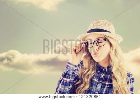 Gorgeous blonde hipster sending air kiss against bright blue sky with cloud