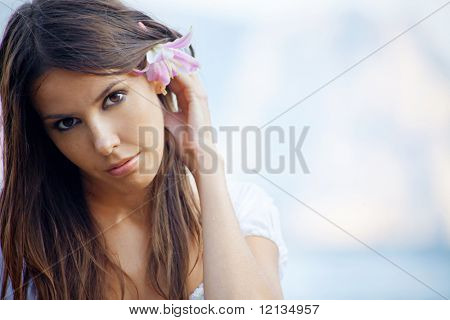 ภาพ Closeup ของผู้หญิงสวยคล้ำกับลิลลี่ในผมวางตัวเหนือทะเล