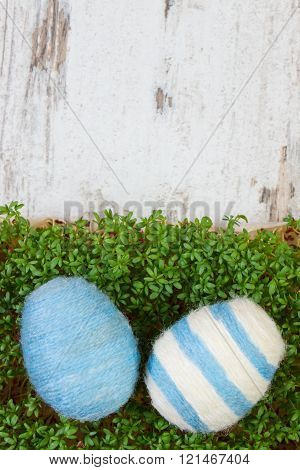 Easter eggs wrapped woolen string and green cress on wooden background, copy space for text, decorat