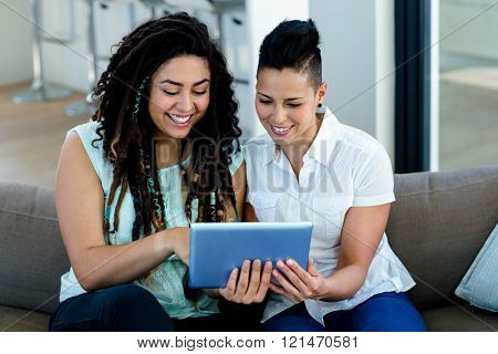 Lesbian couple using digital tablet in living room