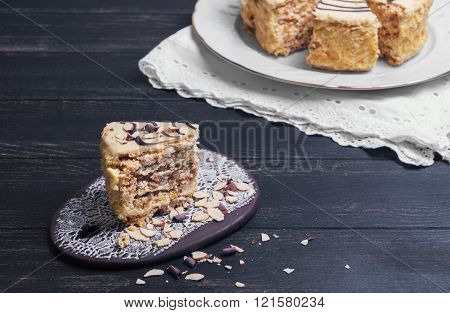Esterhazy cake and a slice on a wooden dark black background on a ceramic board handmade almonds chocolate chips rustic Shabby