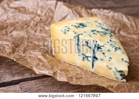 ?heese with a blue mold on the paper on the wooden background